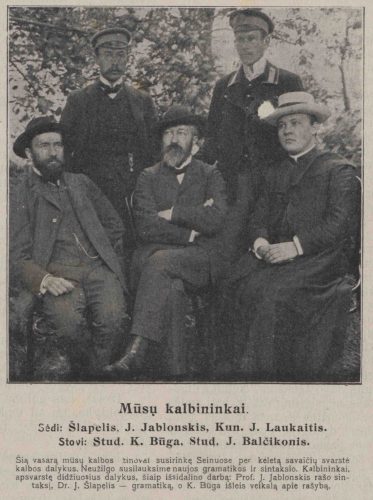 Nuotrauka „Mūsų kalbininkai“ iš 1909 m. leidinio. Sėdi: (iš kairės) J. Šlapelis, J. Jablonskis, Kun. J. Laukaitis. Stovi: Stud. K. Būga, Stud. J. Balčikonis. Apačioje prierašas: „Šią vasarą mūsų kalbos žinovai susirinkę Seinuose per keletą savaičių svarstė kalbos dalykus. Neužilgo susilauksime naujos gramatikos ir sintaksio. Kalbininkai, apsvarstę didžiuosius dalykus, šiaip išsidalino darbą: Prof. J. Jablonskis rašo sintaksį, Dr. J. Šlapelis – gramatiką, o K. Būga išleis veikalą apie rašybą.“