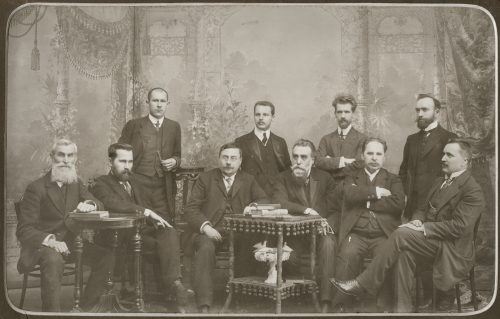 Lietuvių mokslo draugijos komitetas. 1911–1912 m. Sėdi, iš kairės: Juozas Kairiūkštis, Antanas Smetona, prof. August Robert Niemi, Jonas Basanavičius, Antanas Vileišis ir Jonas Vileišis. Stovi, iš kairės: Juozas Balčikonis, Zigmas Žemaitis, Mykolas Biržiška, Jurgis Šlapelis. Antroje nuotraukos pusėje Marijos Šlapelienės visos pavardės užrašytos pieštuku, aukščiau – dar kartą juodu rašalu. Lietuvių mokslo draugija veikė 1907 – 1940 m. ir buvo viena reikšmingiausių kultūros, švietimo ir mokslo organizacijų Vilniaus krašte. Lietuvių mokslo draugiją kartu su bendraminčiais 1907 m.įsteigė daktaras Jonas Basanavičius Steigimo metais Mokslo draugijoje buvo 156 nariai, tarp jų ir Jurgis Šlapelis. Iš viso per draugijos gyvavimą jos veikloje dalyvavo apie 1,5 tūkst. žmonių. Draugijos nariai formavo tautos ir būsimosios Lietuvos valstybės ateitį, jų veikla bei pastangos lietuvių tautą išvedė į Nepriklausomybės siekimo kelią. Pradėta nuo paprastų, bet esminių dalykų: mokyklų visoje šalyje steigimo, lietuviškų vadovėlių ir knygų leidybos.  Iš Lietuvių mokslo draugijos veiklos išsirutuliavo Lietuvos valstybingumo idėja. Iš 20-ies 1918 m. Vasario 16-osios Nepriklausomybės aktą pasirašiusių signatarų net 19 buvo Lietuvių mokslo draugijos nariai. Taip pat trys būsimieji Lietuvos prezidentai – Aleksandras Stulginskis, Kazys Grinius ir Antanas Smetona, du ministrai pirmininkai – Augustinas Voldemaras ir Juozas Tūbelis buvo draugijos nariai.