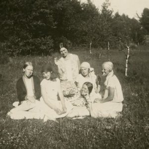 Laimutė ir Gražutė Šlapelytės su keturiom draugėmis Palangoje, pievoje. 1928 m. Gražutė guli viduryje, Laimutė – klūpi pačiame viršuje. Kitoje pusėje užrašyta: „Mergičkos berūkančios… Tik ne papierosus, o „Rūtos“ „Dūdeles“…