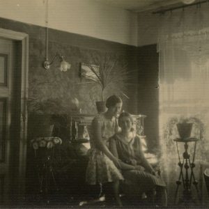 Laimutė Šlapelytė su drauge namuose, Pilies g. 1929 m. Laimutė sėdi savo namų svetainėje su drauge Maryte. Antroje pusėje užrašyta: „Laimučiukas su Maričiuke tarp paduškučių / Vilnius 1929-VII“.